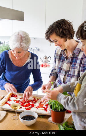 Junge Junge, Mutter und Großmutter pizza gemeinsam in der Küche Stockfoto