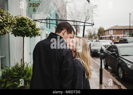 Mitte nach Paar in Street, Küssen, holding Dach Stockfoto