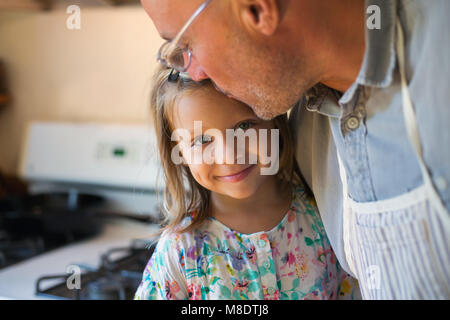 Portrait von Mädchen auf die Stirn geküsst von Vater in der Küche, Stockfoto