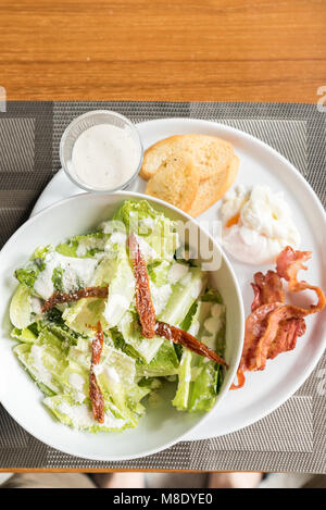 Caesar Salat mit knusprigem Speck und Eier pochieren serviert. Stockfoto