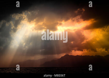 Schwarz stürmischen Himmel über das Tyrrhenische Meer und Berge Silhouette mit orange Sonnenstrahlen durch die Wolken mit Herz Form in der es scheint. Salerno, südlichen Es Stockfoto