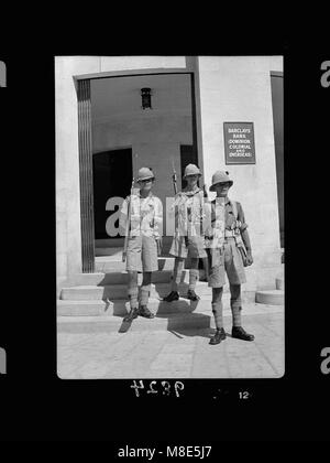 Ein Nahfoto eines Offiziers und Soldaten, die in einem Bankeingang bei Barclay's Bank in Jerusalem positioniert sind. Dieses Bild fängt wahrscheinlich einen angespannten Moment während einer Zeit des Konflikts oder der militärischen Besatzung in der Region ein. Stockfoto