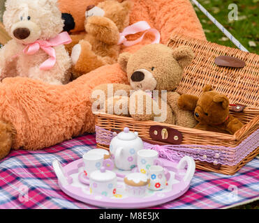 Kuschelig weiche Teddybären mit einem Picknickkorb und Tee im Sommer. Stockfoto