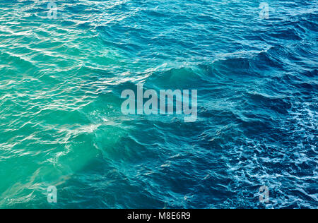 Kleine Wellen und Wellen auf blauem Meerwasser reflektieren helles Sonnenlicht am Sommertag Stockfoto