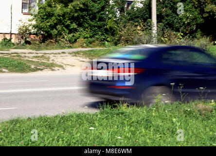 Geschwindigkeitsüberschreitung-Konzept - Bewegung verwischt Auto schnell auf eine kleine Straße den Berg hinauf gehen Stockfoto