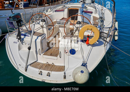 Weißes, glänzendes Motorboot mit modernem Design, das am Pier mit Seilen auf blauem Meerwasser festgemacht ist, das am Sommertag helles Sonnenlicht reflektiert Stockfoto