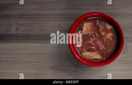 Chinesische bihuhn Suppe in einer roten Schüssel auf einem Bambus Board serviert. Stockfoto