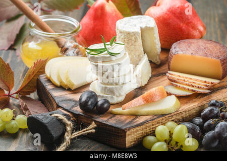 Der Käse mit Obst und Honig. Camembert. Bree. Trauben, Birnen und Rosmarin. Wein Snacks für Feinschmecker. Selektiver Fokus Stockfoto