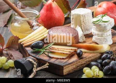 Der Käse mit Obst und Honig. Camembert. Bree. Trauben, Birnen und Rosmarin. Wein Snacks für Feinschmecker. Selektiver Fokus Stockfoto