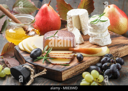 Der Käse mit Obst und Honig. Camembert. Bree. Trauben, Birnen und Rosmarin. Wein Snacks für Feinschmecker. Selektiver Fokus Stockfoto