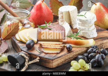 Der Käse mit Obst und Honig. Camembert. Bree. Trauben, Birnen und Rosmarin. Wein Snacks für Feinschmecker. Selektiver Fokus Stockfoto