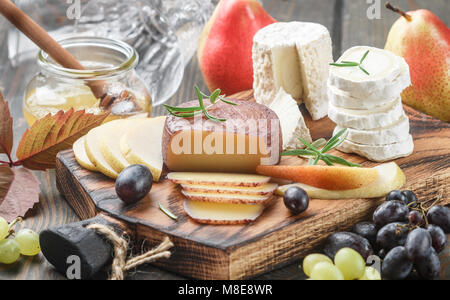 Der Käse mit Obst und Honig. Camembert. Bree. Trauben, Birnen und Rosmarin. Wein Snacks für Feinschmecker. Selektiver Fokus Stockfoto