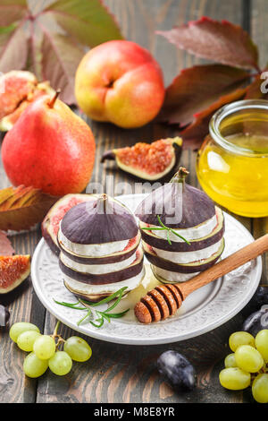 Vorspeise von Feigen und Ziegenkäse mit Honig. 2-in-1-Salat von Gourmet. Birnen, Trauben und Rosmarin auf dem Tisch. Selektiver Fokus Stockfoto