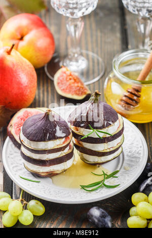 Vorspeise von Feigen und Ziegenkäse mit Honig. 2-in-1-Salat von Gourmet. Birnen, Trauben und Rosmarin auf dem Tisch. Selektiver Fokus Stockfoto