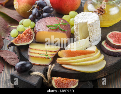 Der Käse mit Obst und Honig. Camembert. Bree. Trauben, Feigen, Birnen, und Rosmarin. Wein Snacks für Feinschmecker. Selektiver Fokus Stockfoto