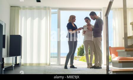 Professionelle Immobilien Agent zeigt ein stilvolles, modernes Haus mit einem schönen jungen Paar, das auf dem Markt für den Kauf/Miete neues Zuhause sind. Stockfoto