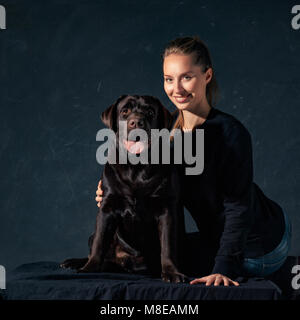 Die junge Frau umarmt einen Mix Rasse Hund Stockfoto