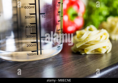 100ccm / 100ml Of Water In A Measuring Cup On A Kitchen Counter With Food Stockfoto