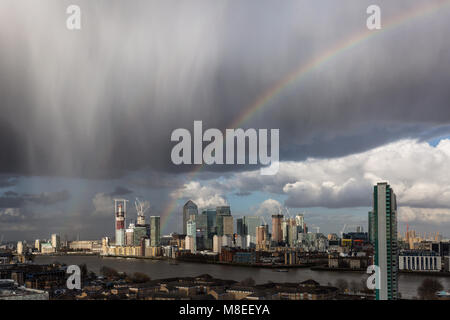 London, Großbritannien. 16. März, 2018. UK Wetter: Ein Regenbogen bricht über Canary Wharf business park Gebäude in East London während einem Nachmittag Regensturm. © Guy Corbishley/Alamy leben Nachrichten Stockfoto