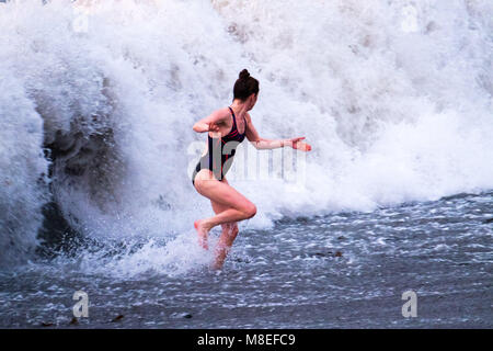 Aberystwyth Wales UK, Freitag, 16. März 2018 Deutschland Wetter: Am Ende eines milden Frühling am Nachmittag, eine junge Frau für eine braciung Abend geht in den Gewässern der Cardigan Bay schwimmen Aberystwyth an der Westküste von Wales das Met Office hat eine Reihe von Gelb und Gelb Warnungen für Schnee und Eis für das Wochenende, als Blast sehr kalte Luft bläst in aus dem Osten Foto © Keith Morris/Alamy leben Nachrichten Stockfoto