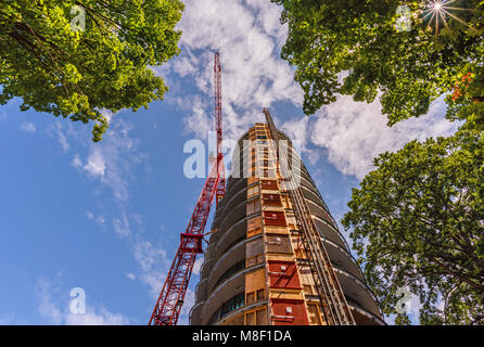 Ansicht von unten nach oben über den Bau eines Turmdrehkrans, einem mehrstöckigen Gebäude an einem Sommertag vor einem blauen Himmel und weißen Wolken Stockfoto