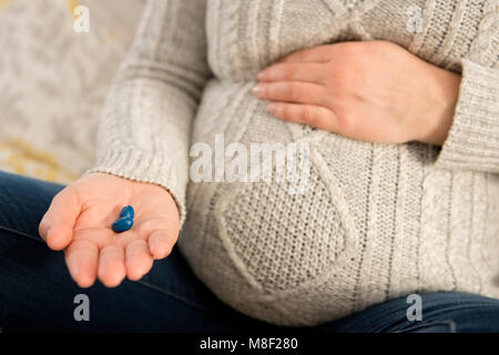 Schwangere Frau mit Pillen in der Hand Stockfoto
