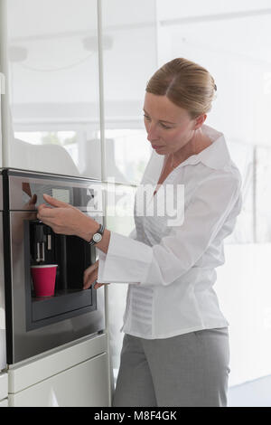 Reife Frau Kaffee in der modernen Küche Stockfoto