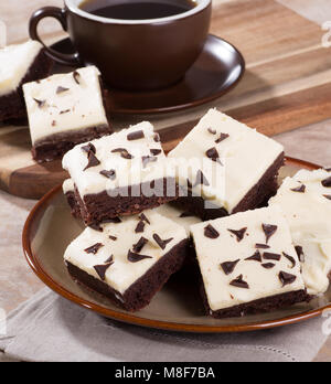 Stapel der Chocolate Fudge brownies auf einer Platte mit einer Tasse Kaffee im Hintergrund Stockfoto