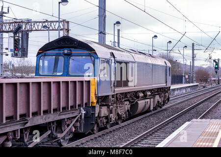 Eine Fracht Diesel Lokomotive zieht einen Zug von niedrigen seitig Metall Drehgestelle Stockfoto