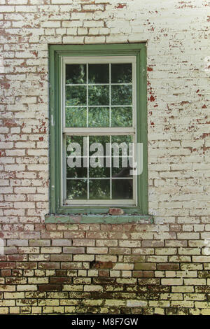 Grüner Bereich Glas Fenster gegen verwitterten gegen weißen und roten Ziegelmauer eingerahmt Stockfoto