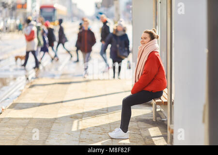 Junge hübsche Mädchen auf der Bank sitzen in der Nähe von Straßenbahn- und Warten Stockfoto