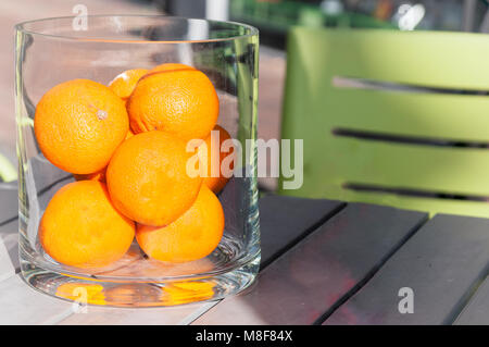 Orangen in einem großen Glas auf einem Tisch Stockfoto