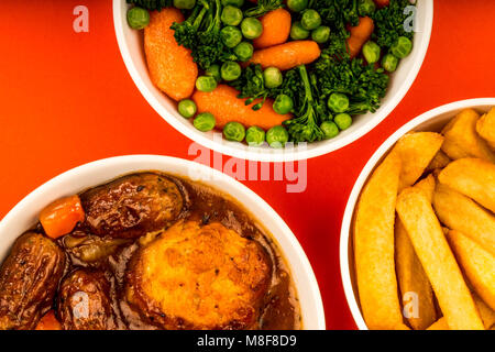 Traditionelle britische Lincolnshire Wurst Schuster auf rotem Hintergrund mit einer Schüssel mit gemischtem Gemüse und Chips oder Pommes Frites Stockfoto