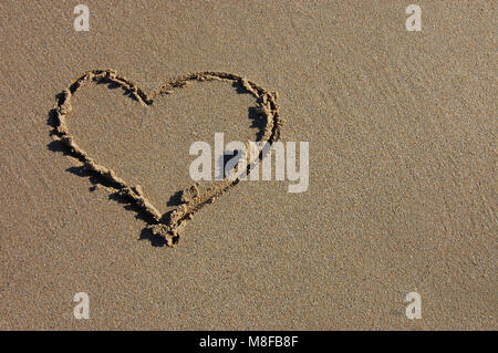 Einen Hintergrund mit ein Herz in den Sand des Strandes gezeichnet Stockfoto