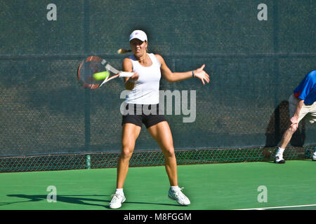 Anna Tatishvili in grauen Hemd und weißen Rock Tennis ball mit Schläger an sonnigen Green Court. Stockfoto