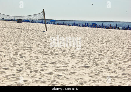 Weißer Sandstrand mit Volleyballnetz und Zeile liegen entlang der Küste Stockfoto