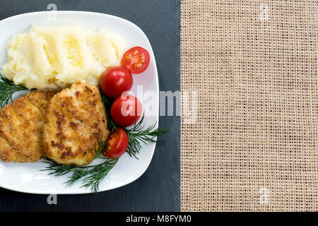 Zwei saftig gebratenes Fleisch Frikadellen auf eine weiße Platte mit Cherry Tomaten und Kartoffelbrei. Stockfoto