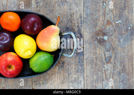 Gemischtes Obst Äpfel, Limette, Zitrone, Birnen und Pflaumen in Metall Fach auf Holz Tisch mit Kopieren nach rechts Stockfoto