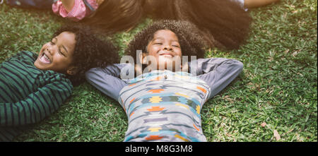 Glückliche Kinder Kinder Festlegung auf Gras im Park Stockfoto