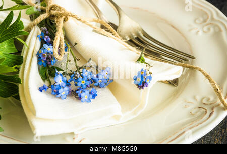 Sommer Blumen Tischdekoration mit leuchtend blauen Vergissmeinnicht Blumen auf Holztisch Stockfoto