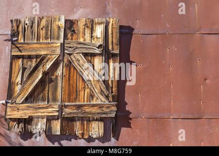 Old Wood Fenster geschlossen an rostfarbener Old Metal Wall of verlassenes Haus Stockfoto