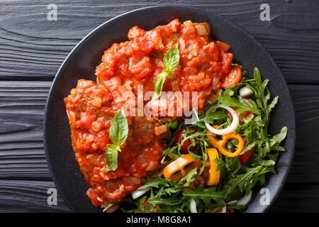 Italienische Rindfleisch Pizzaiola und frisches Gemüse Salat close-up auf einem Teller auf dem Tisch. horizontal oben Ansicht von oben Stockfoto