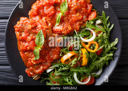 Rindersteak mit pizzaiola Sauce und frischen Salat close-up auf einem Teller. horizontal oben Ansicht von oben Stockfoto