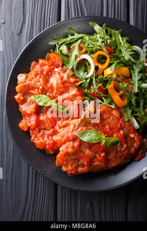 Italienische Rindfleisch Pizzaiola und frisches Gemüse Salat close-up auf einem Teller auf dem Tisch. Vertikal oben Ansicht von oben Stockfoto