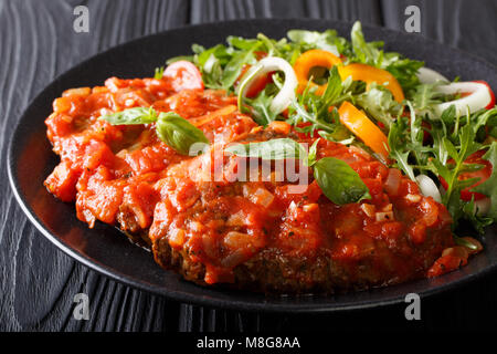 Italienische Rindfleisch Pizzaiola und frisches Gemüse Salat close-up auf einem Teller auf dem Tisch. Horizontale Stockfoto