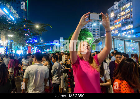 Ein Tourist nimmt ein Foto von den Menschenmassen, die sich versammelt hatten chinesische Mondjahr in Ho Chi Minh City, Saigon, Vietnam zu feiern. Stockfoto