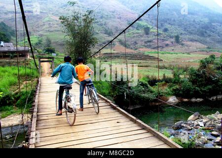 Ha Giang, Vietnam - März 17, 2018: Kinder beim Überqueren einer Holzbrücke mit Fahrrädern in der Region Ha Giang in Vietnam. Stockfoto