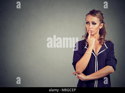 Junge schöne Frau mit den Finger auf die Lippen suchen in Achtsamkeit. Stockfoto