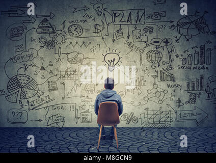 Ansicht von hinten von einem Mann sitzen vor der Wand mit Strategie und Business Plan erstellen. Stockfoto