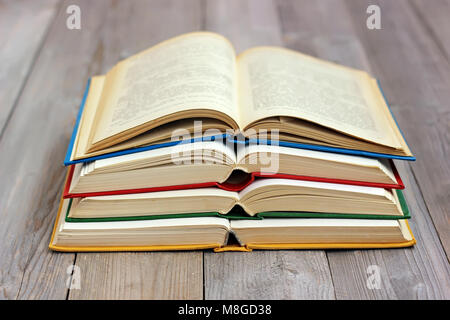 Vier offene Bücher in den farbigen Abdeckung auf dem Tisch aus Brettern. Stockfoto
